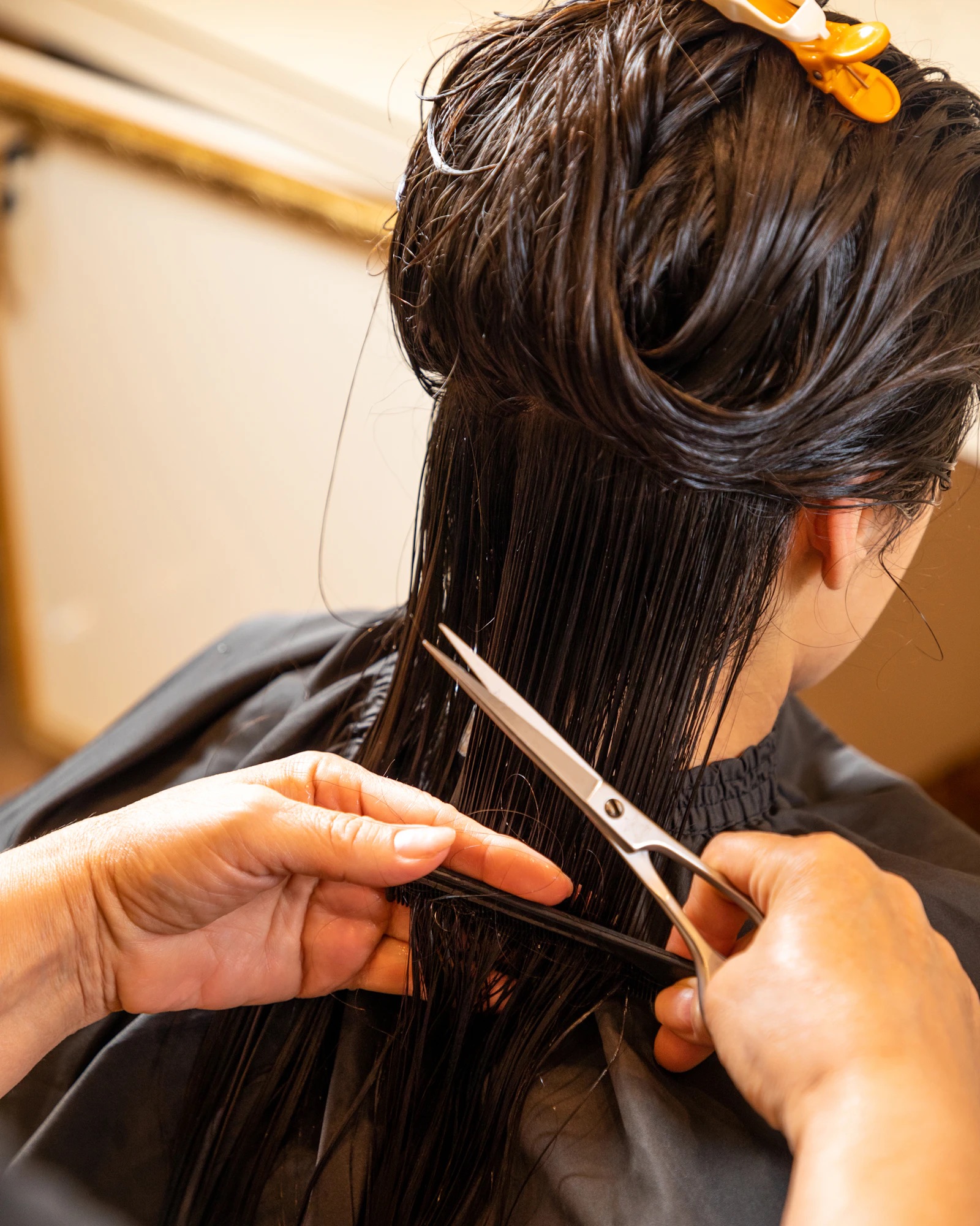 Stylist cutting a client's hair with scissors in a bright studio